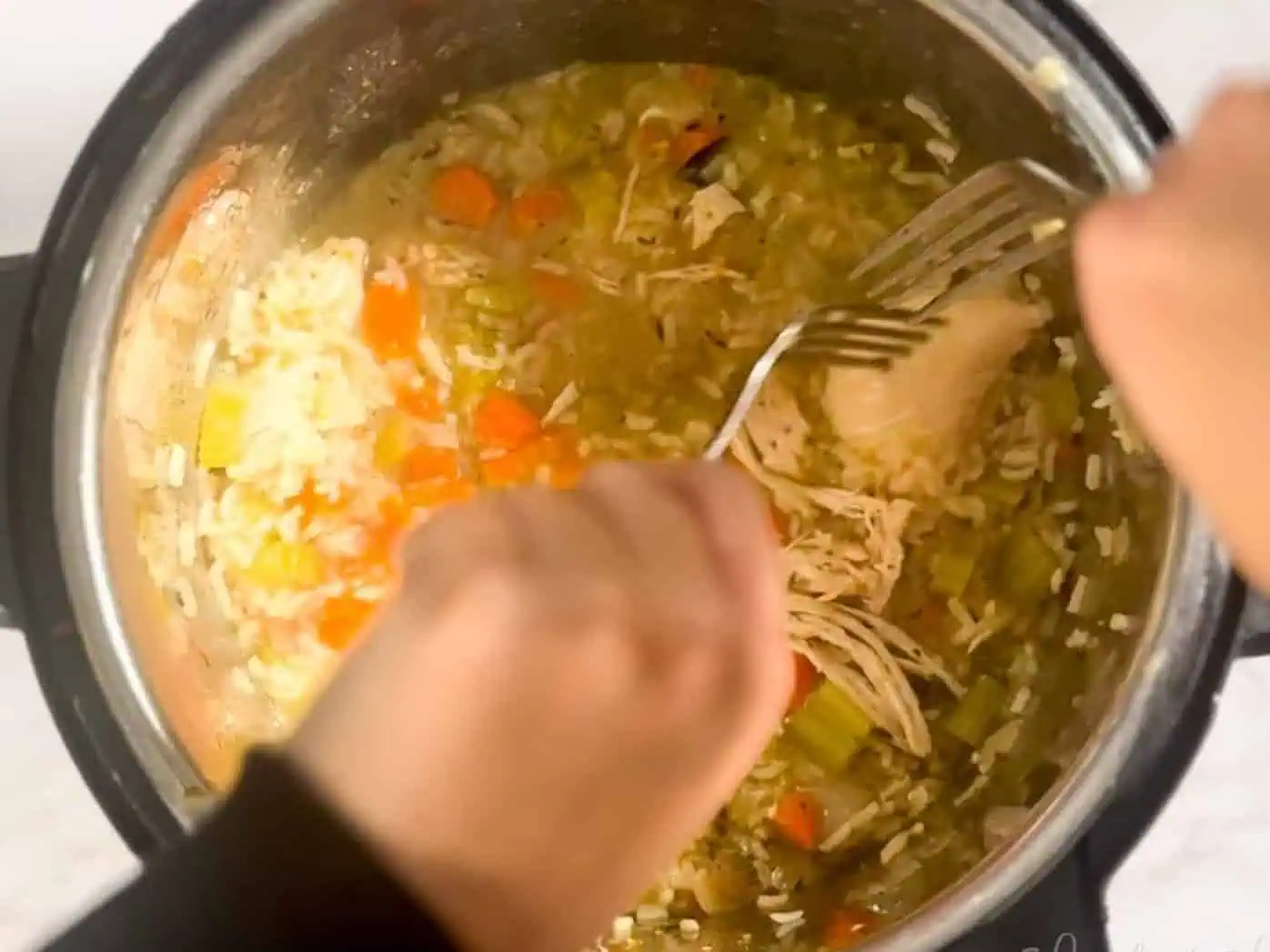shredding chicken with two forks after soup has cooked.