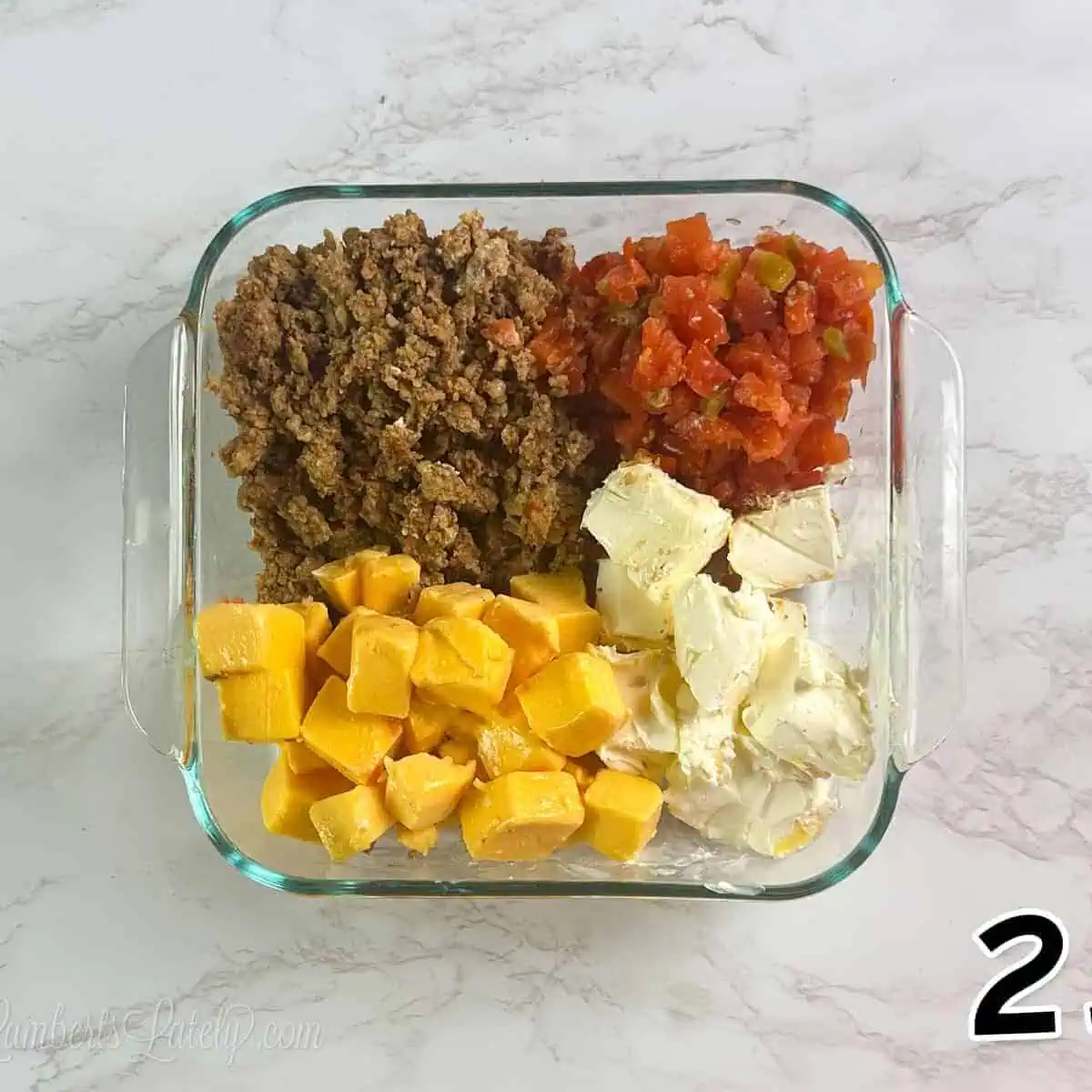 Ground beef, diced tomatoes, cheese, and cream cheese in a glass dish.