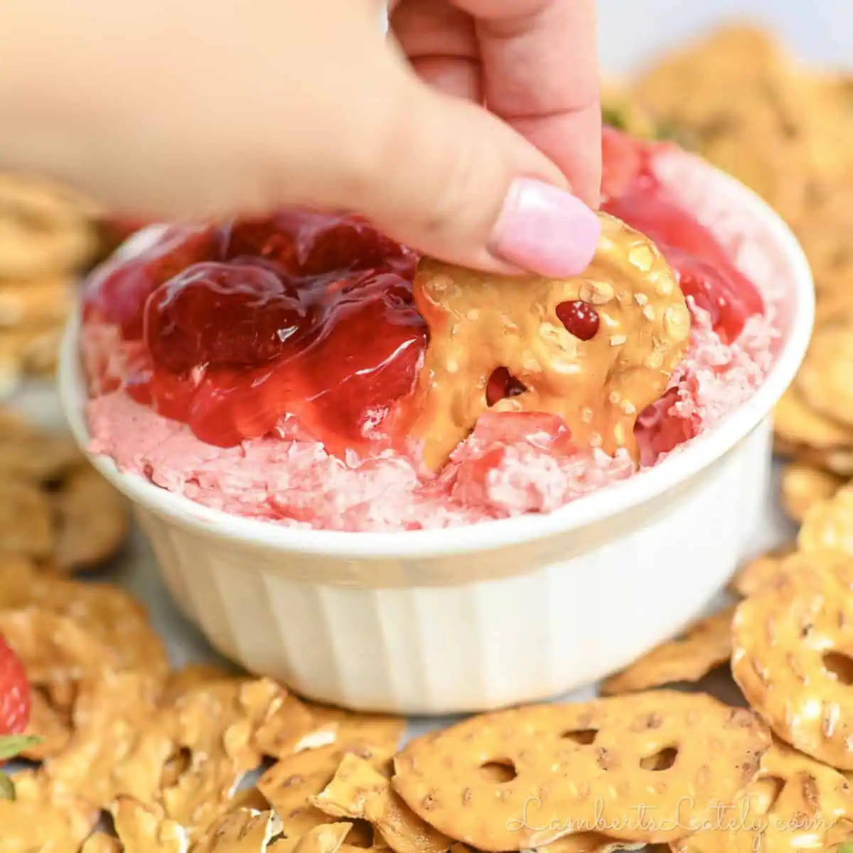 scooping strawberry pretzel salad dip with a pretzel chip.