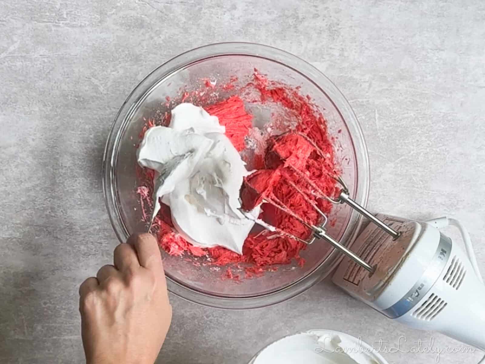 mixing cool whip into the bowl of mixed ingredients.