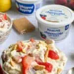 Strawberry banana cheesecake salad with whipped topping and graham cracker crumbs.