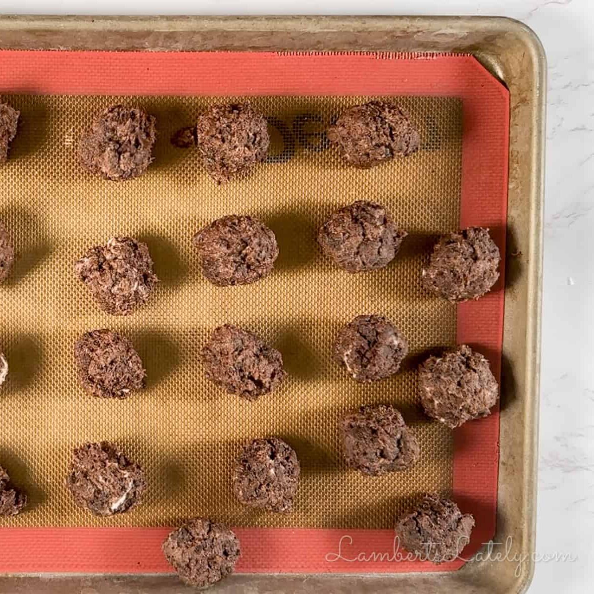 rolled brownie cake balls on a baking sheet.