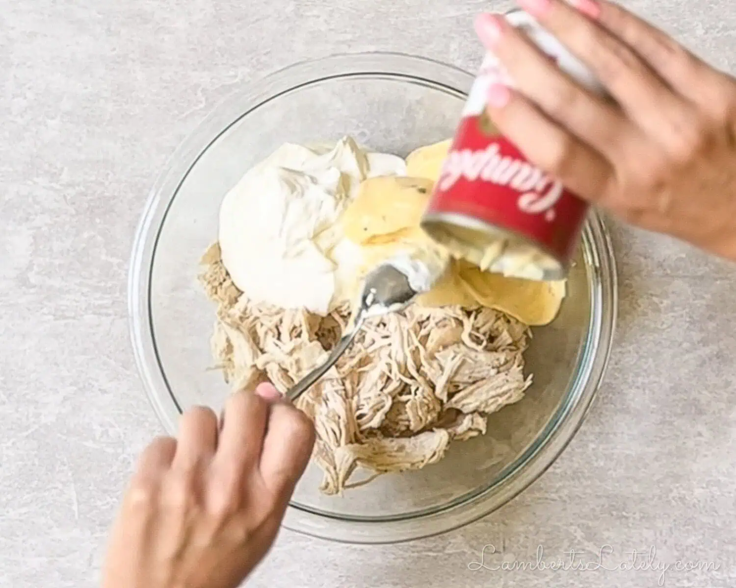 adding soup, sour cream, and shredded chicken to a mixing bowl.