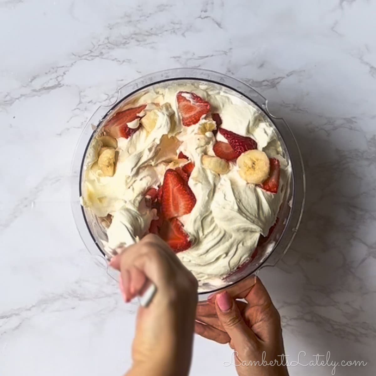 stirring together whipped topping mixture and strawberries/bananas.