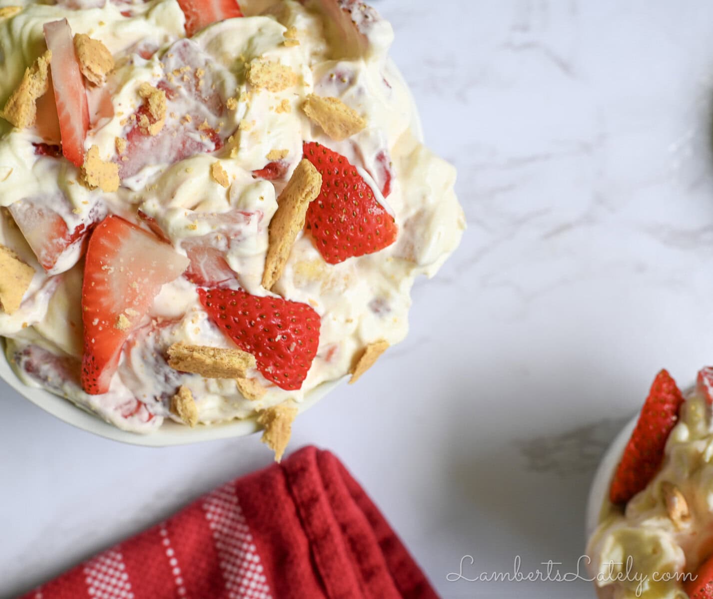 a bowl of strawberry banana cheesecake salad next to a napkin.