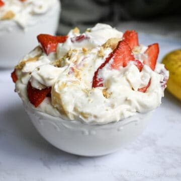 a bowl of strawberry banana cheesecake salad in front of other bowls, a banana.