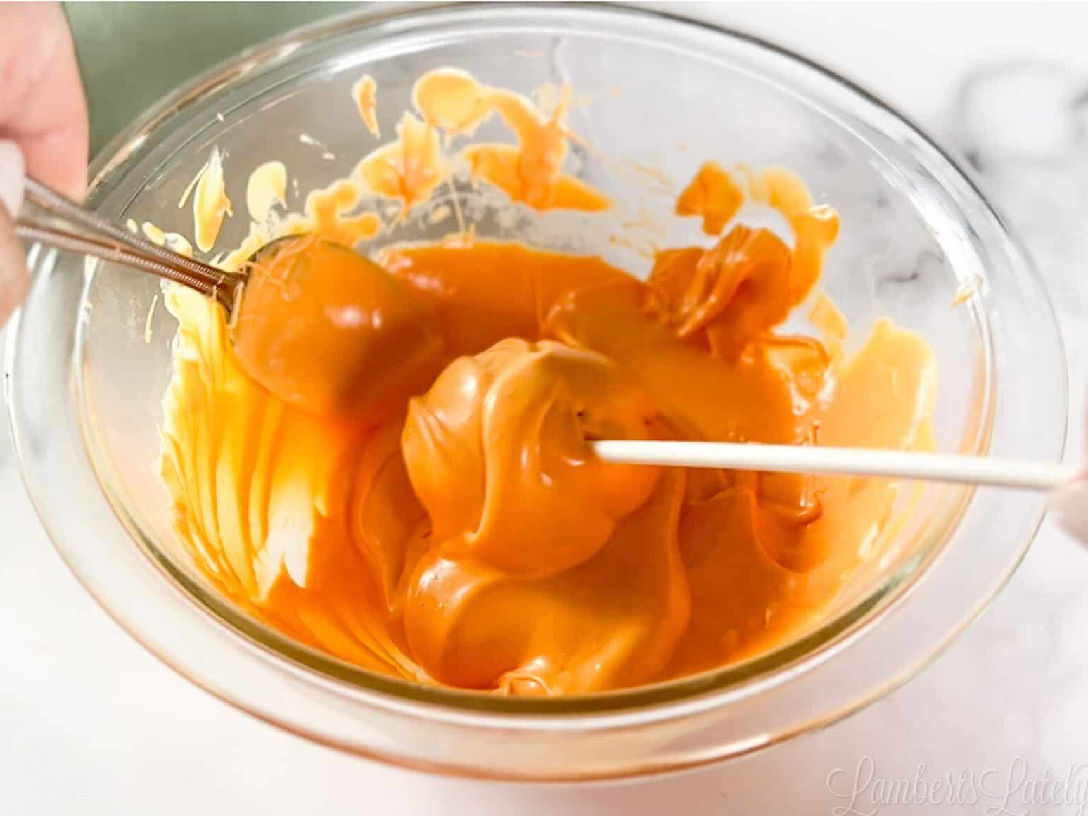 dipping cake pop in orange melted candy.