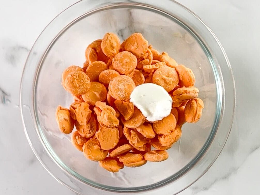 orange candy melts and crisco in a glass bowl.