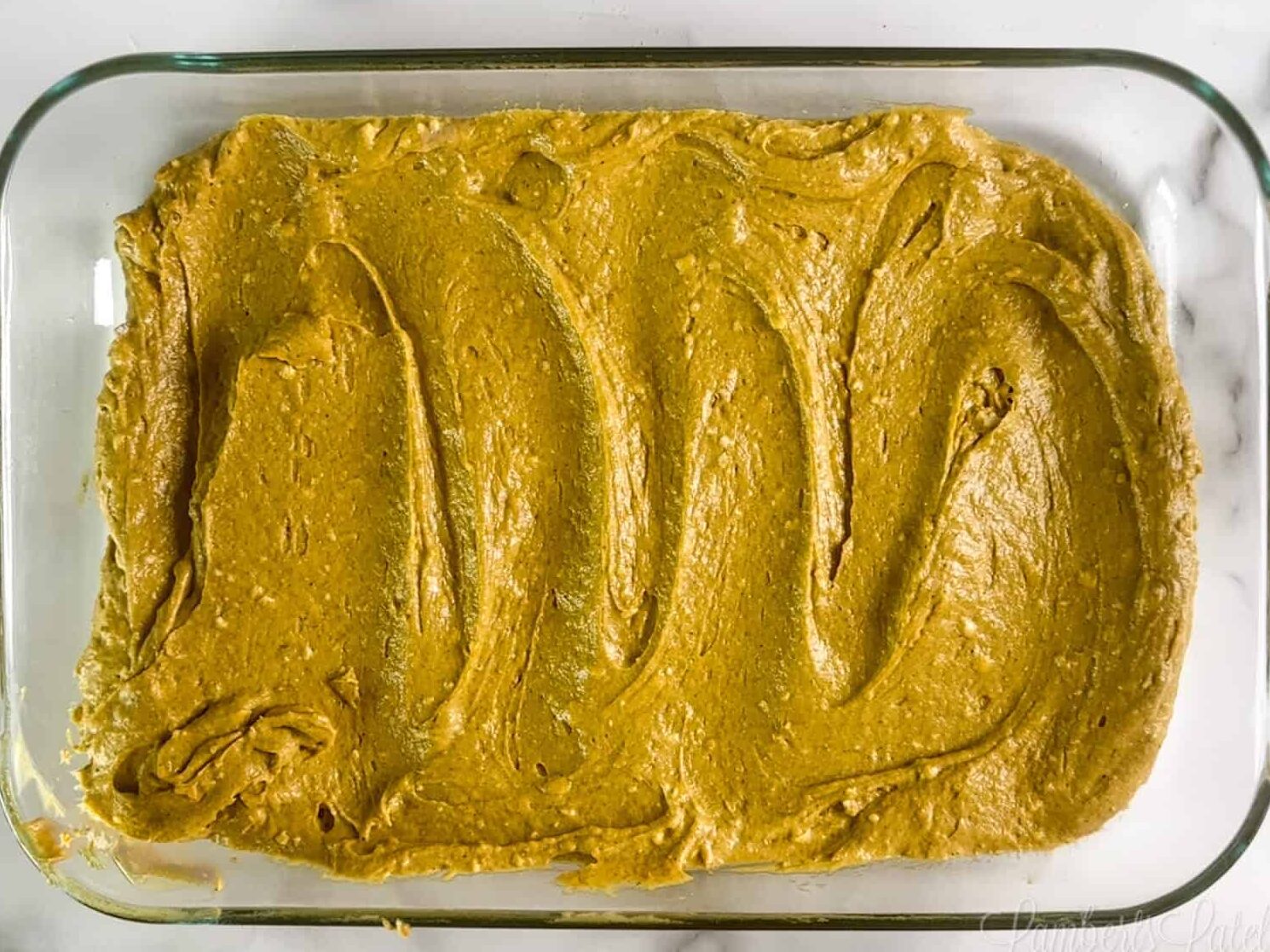 pumpkin cake base batter spread in a baking dish.