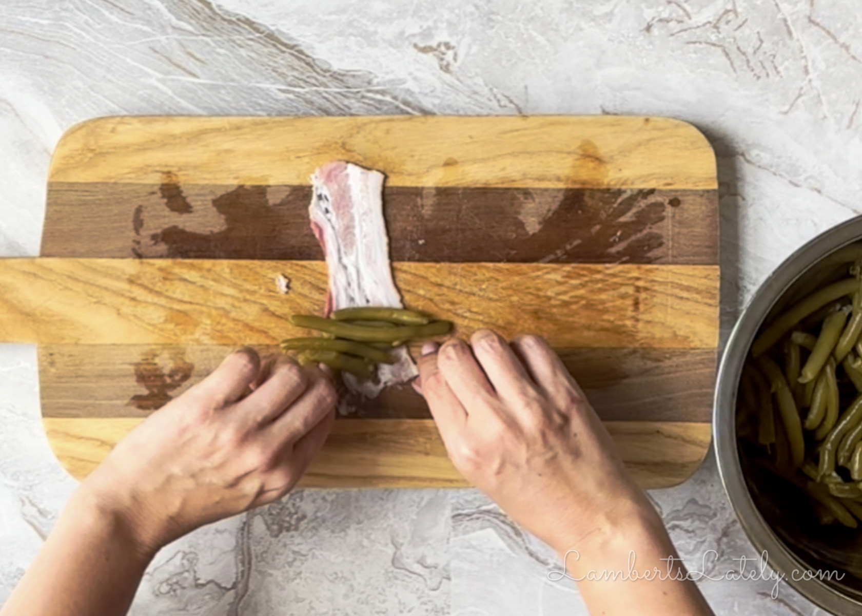 rolling canned green beans in cut bacon strips for green bean bundles.