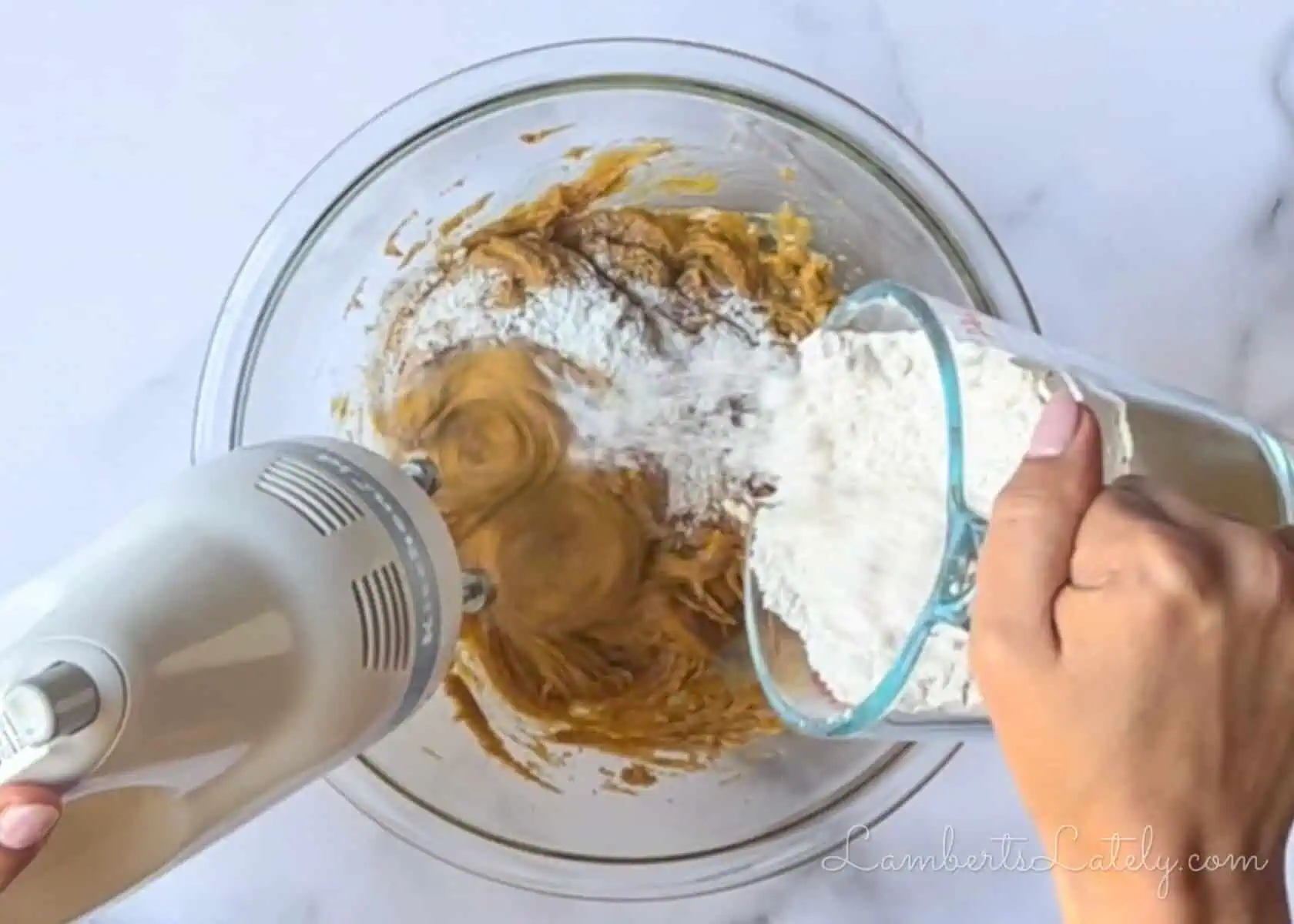 adding flour to the wet ingredients in a large glass bowl.