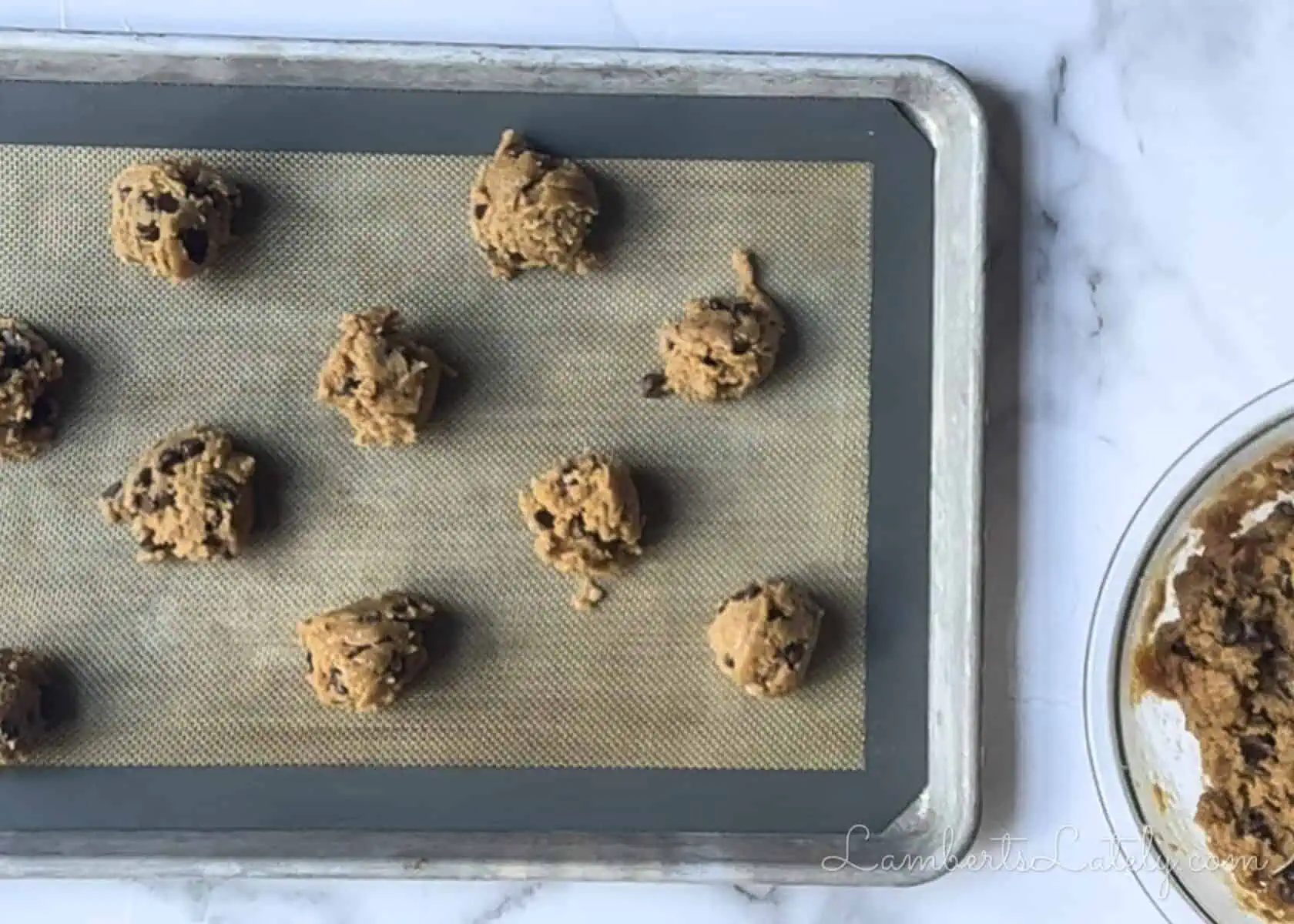 2 tablespoon scoops of peanut butter chocolate chip cookie dough on a lined baking sheet.