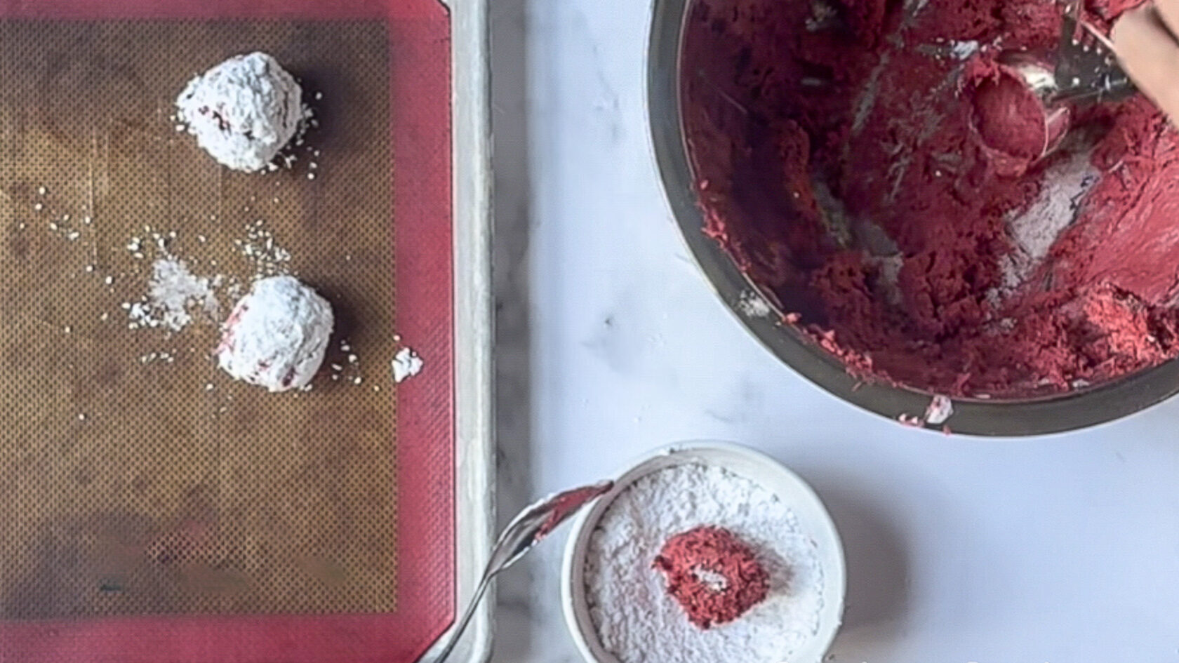 rolling small cookie dough balls in powdered sugar before putting them on a pan.