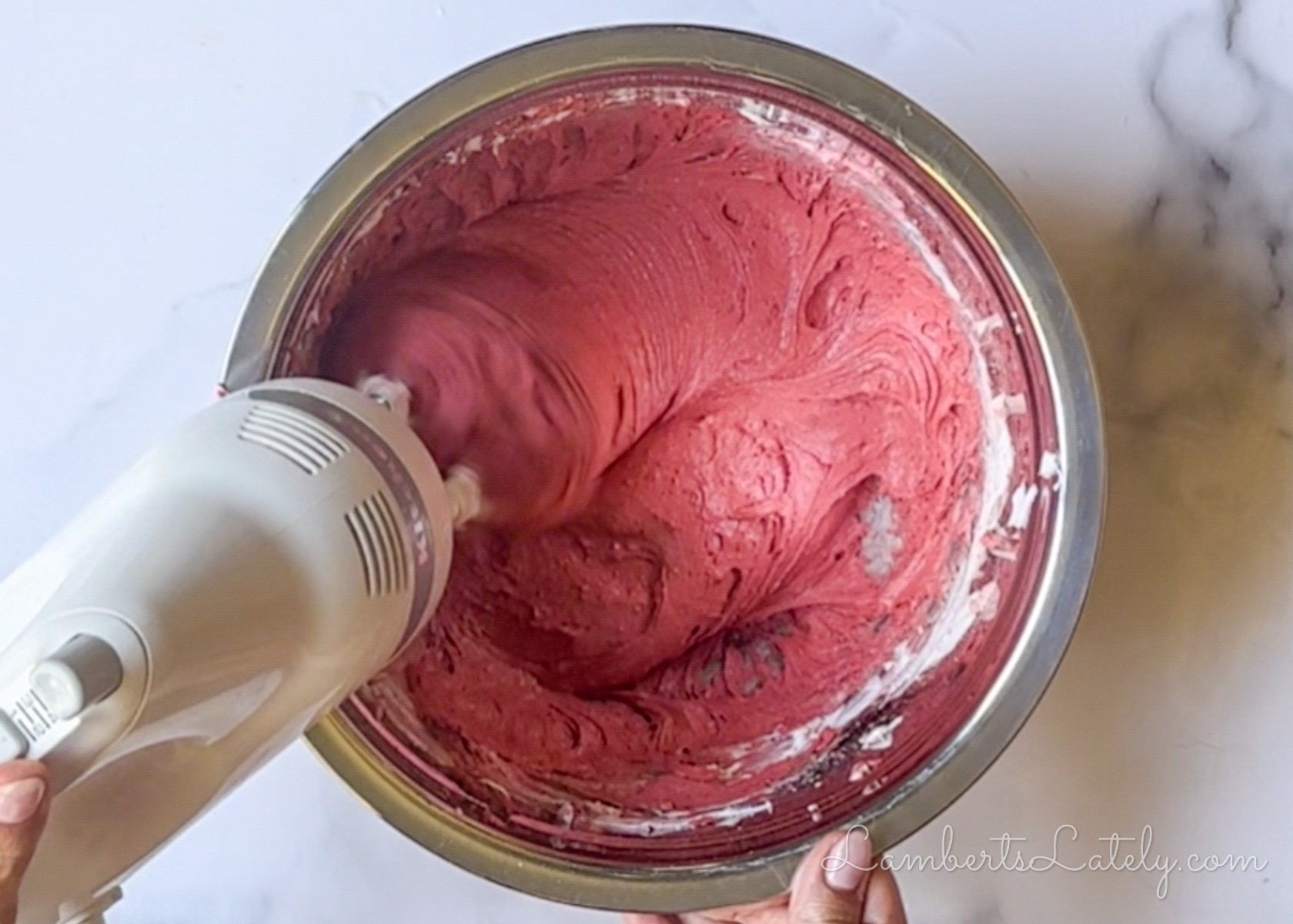 mixing red velvet cookie batter with a hand mixer.