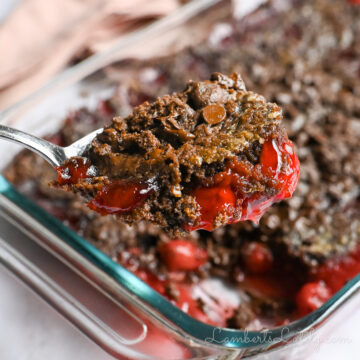 holding a spoonful of cherry chocolate dump cake in front of the baking dish.