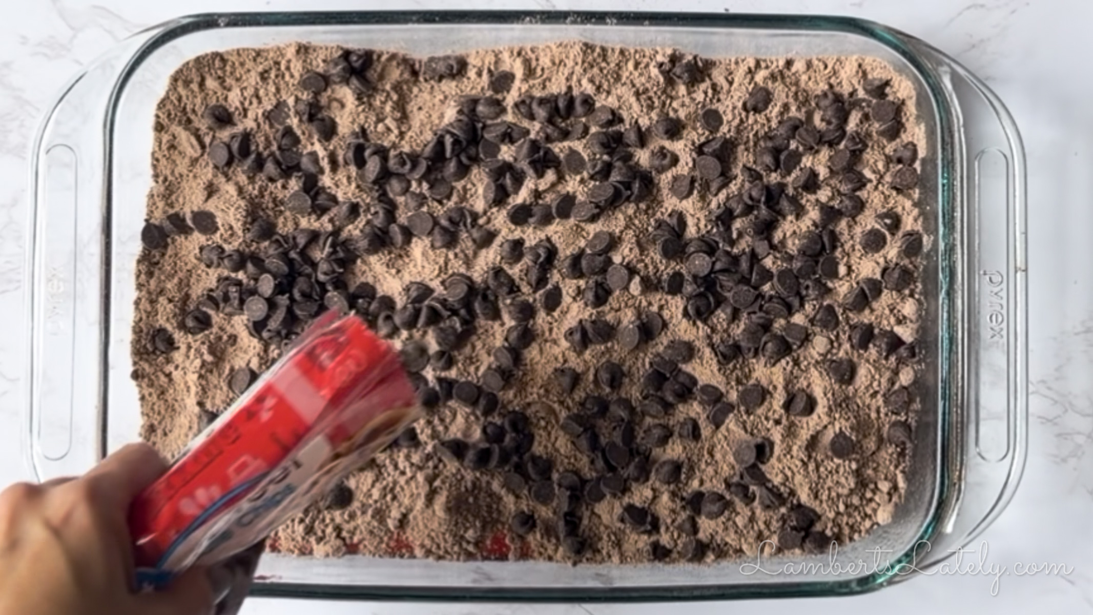 pouring chocolate chips over brownie mix.
