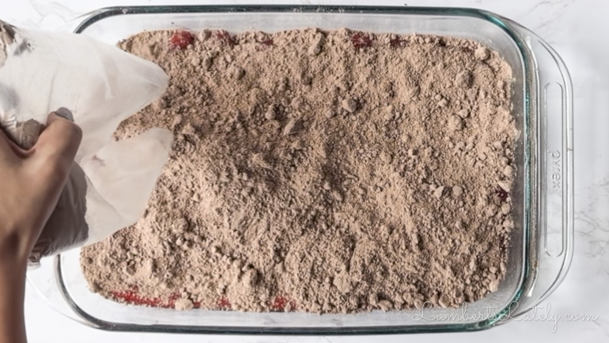 pouring dry chocolate brownie mix over cherry pie filling.