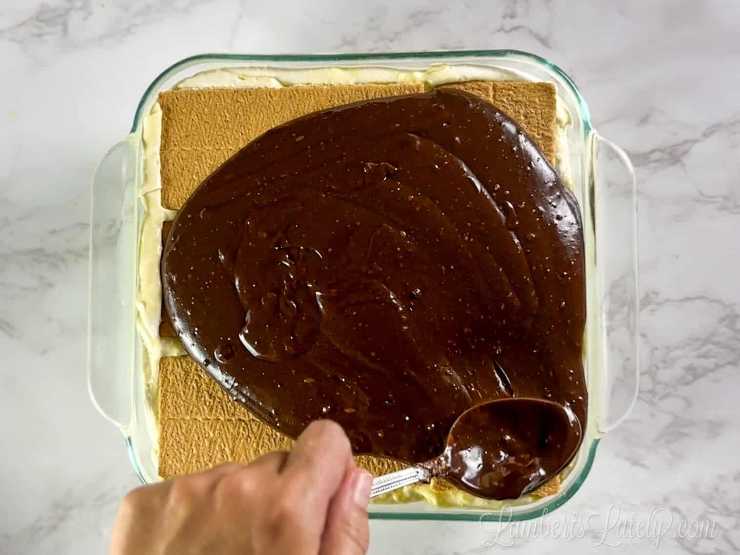 pouring chocolate ganache over eclair cake base.