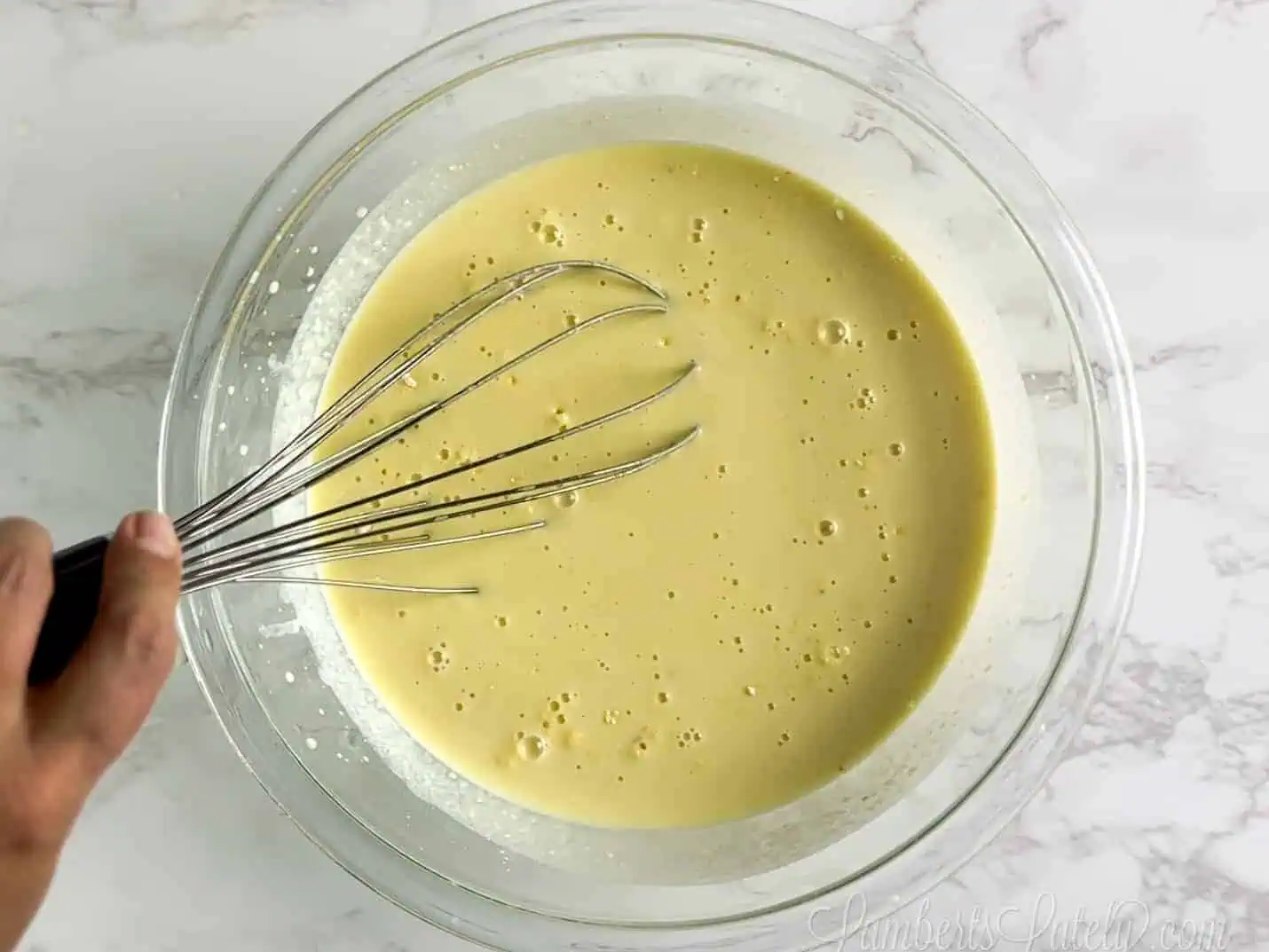 whisking pudding mix in a glass bowl.