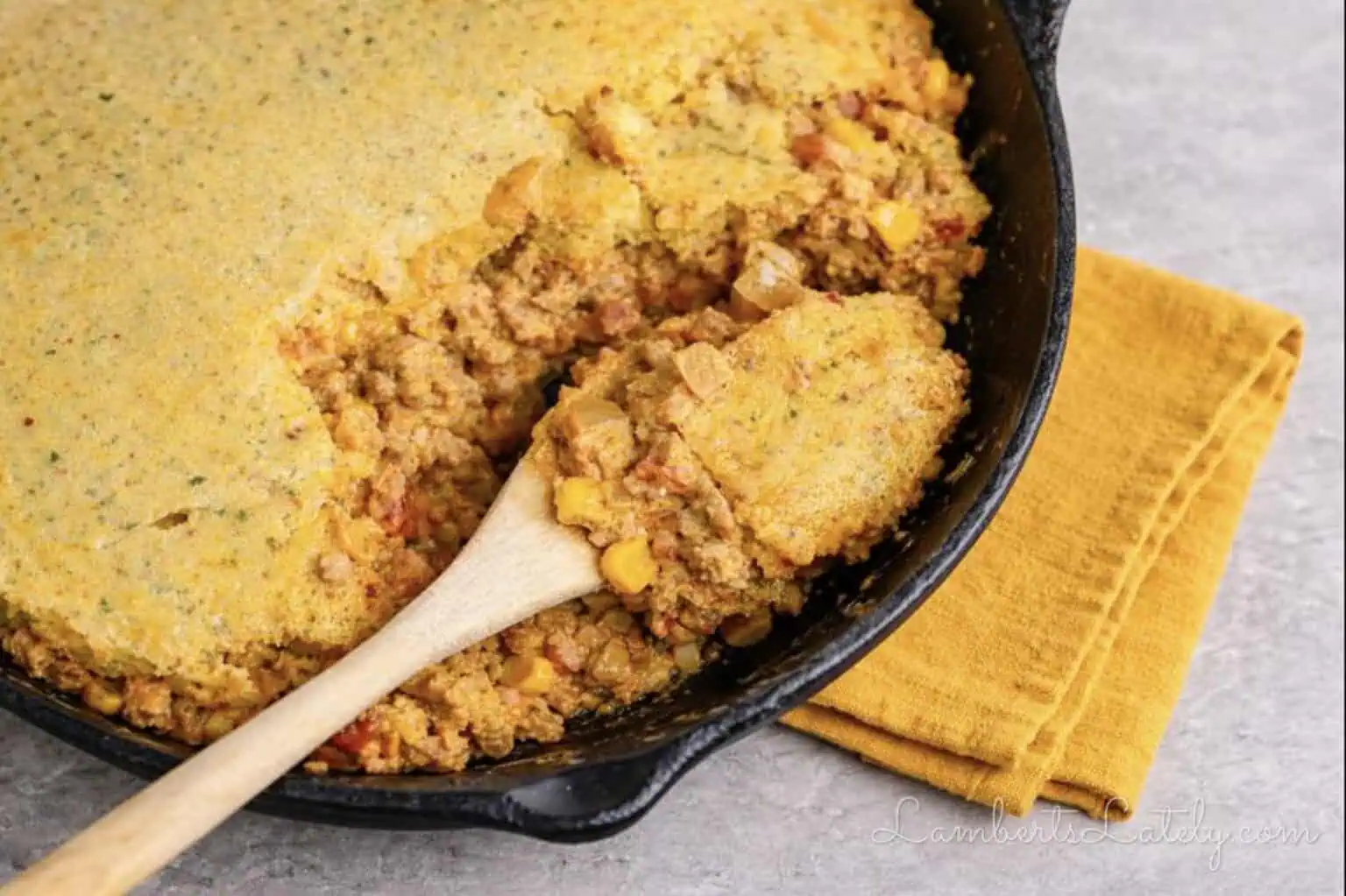 spoon in a cowboy casserole in a cast iron skillet.