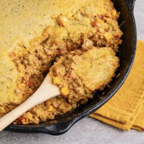 spoon in a cowboy casserole in a cast iron skillet.