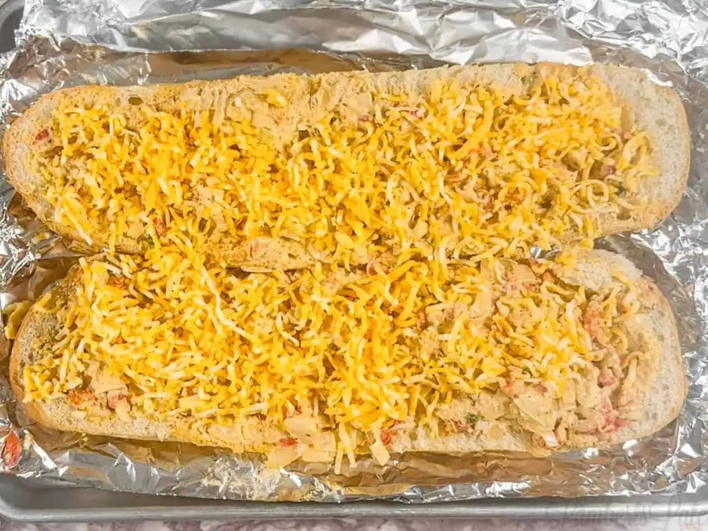 loaves of crawfish bread covered in unmelted cheese.