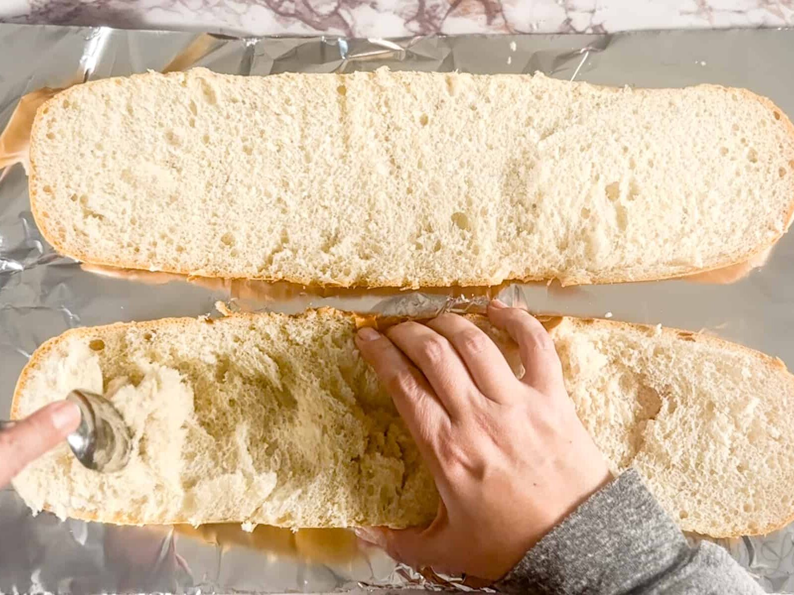 scraping the inside out of a loaf of french bread.