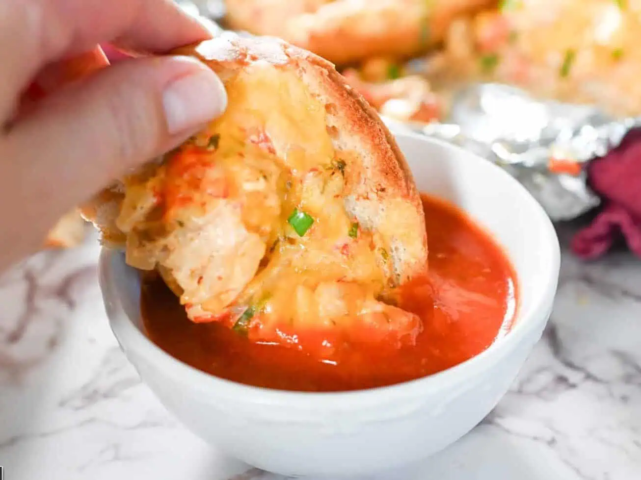 dipping a piece of crawfish bread in marinara sauce.