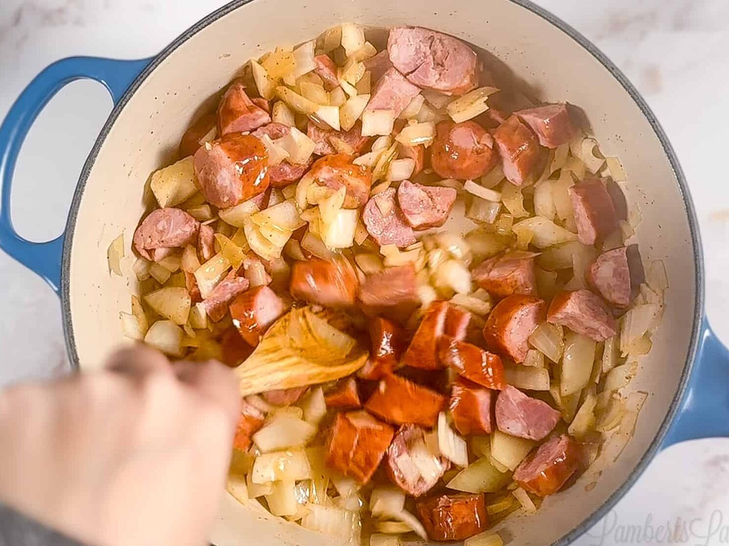 sausage and onions cooking in a pot.
