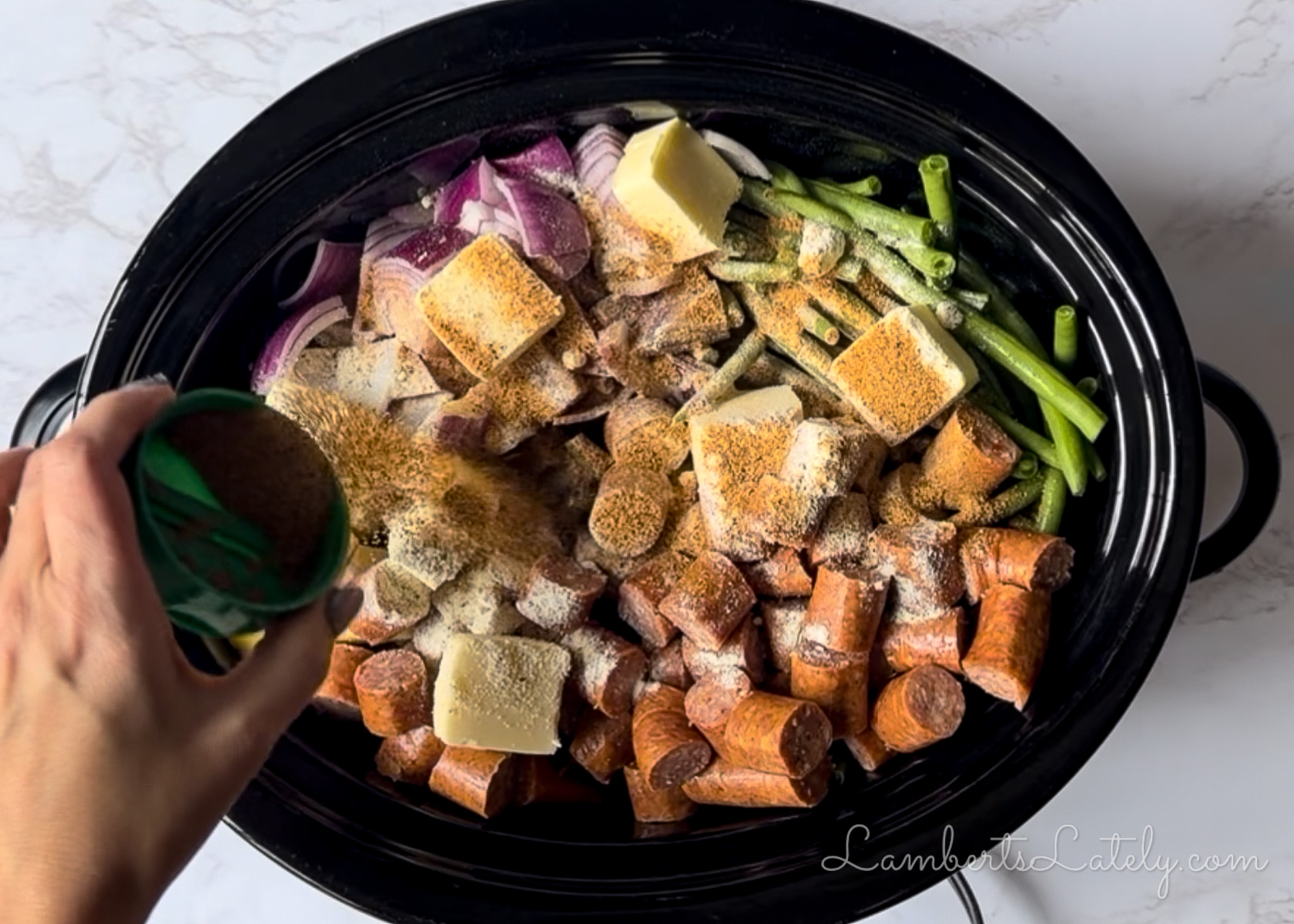 sprinkling seasonings over the sausage and vegetables in the crock pot.