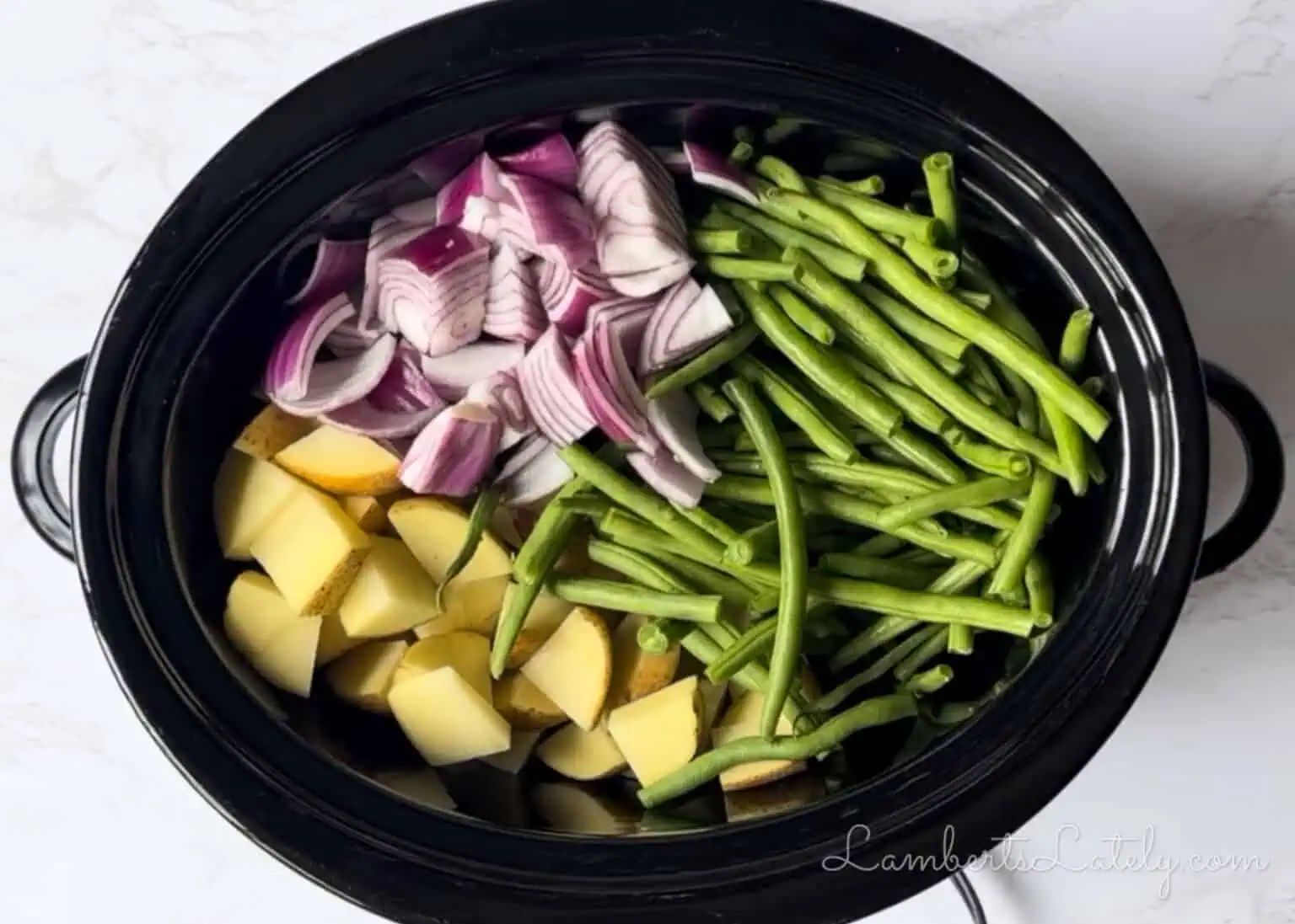 chopped potatoes, red onion, and green beans in a slow cooker.