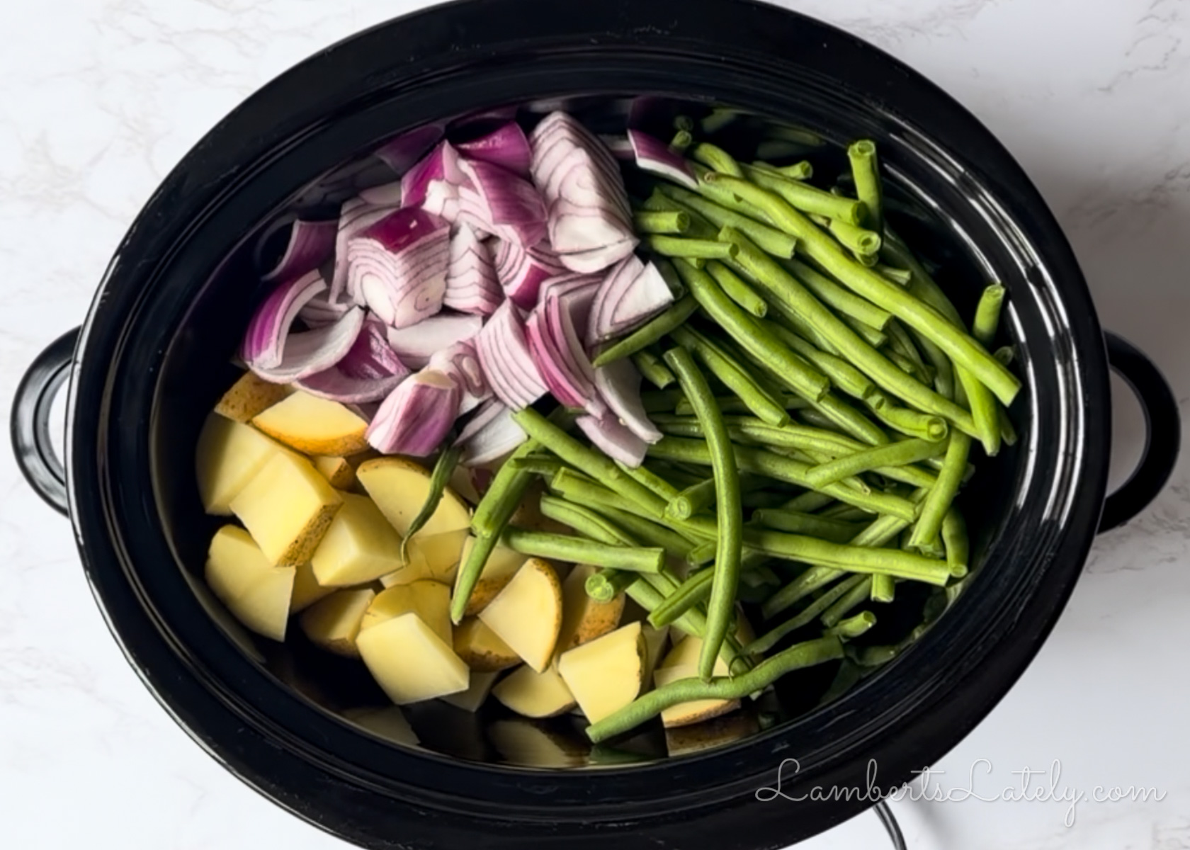 chopped potatoes, red onion, and green beans in a slow cooker.