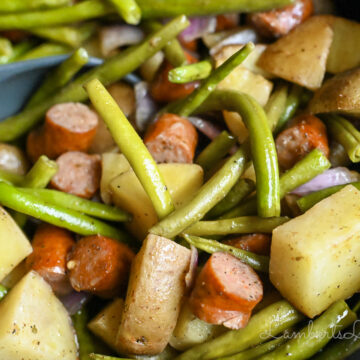 swamp potatoes with green beans, red onion, and sausage in a crock pot.