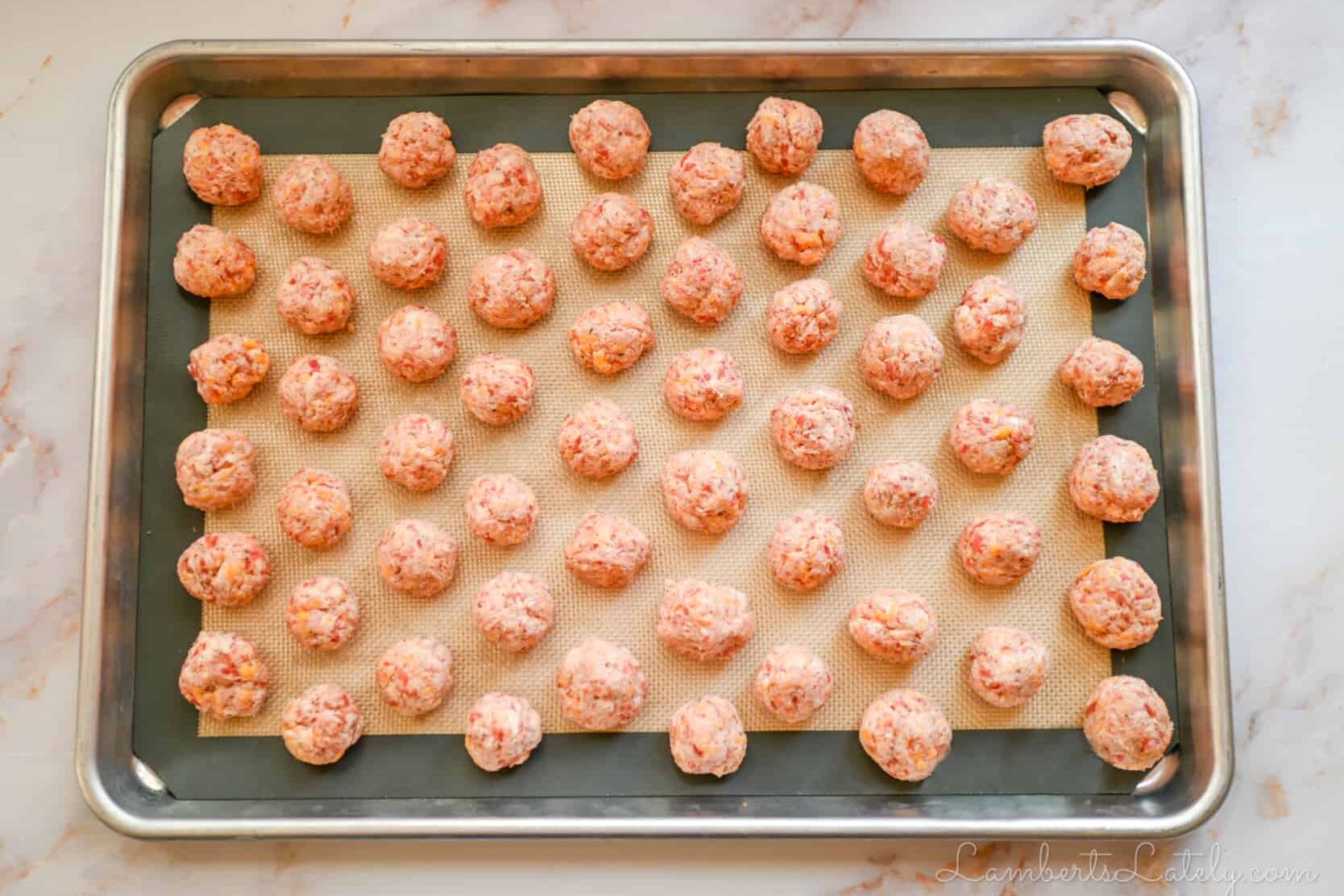 rolled sausage balls on a cookie sheet.