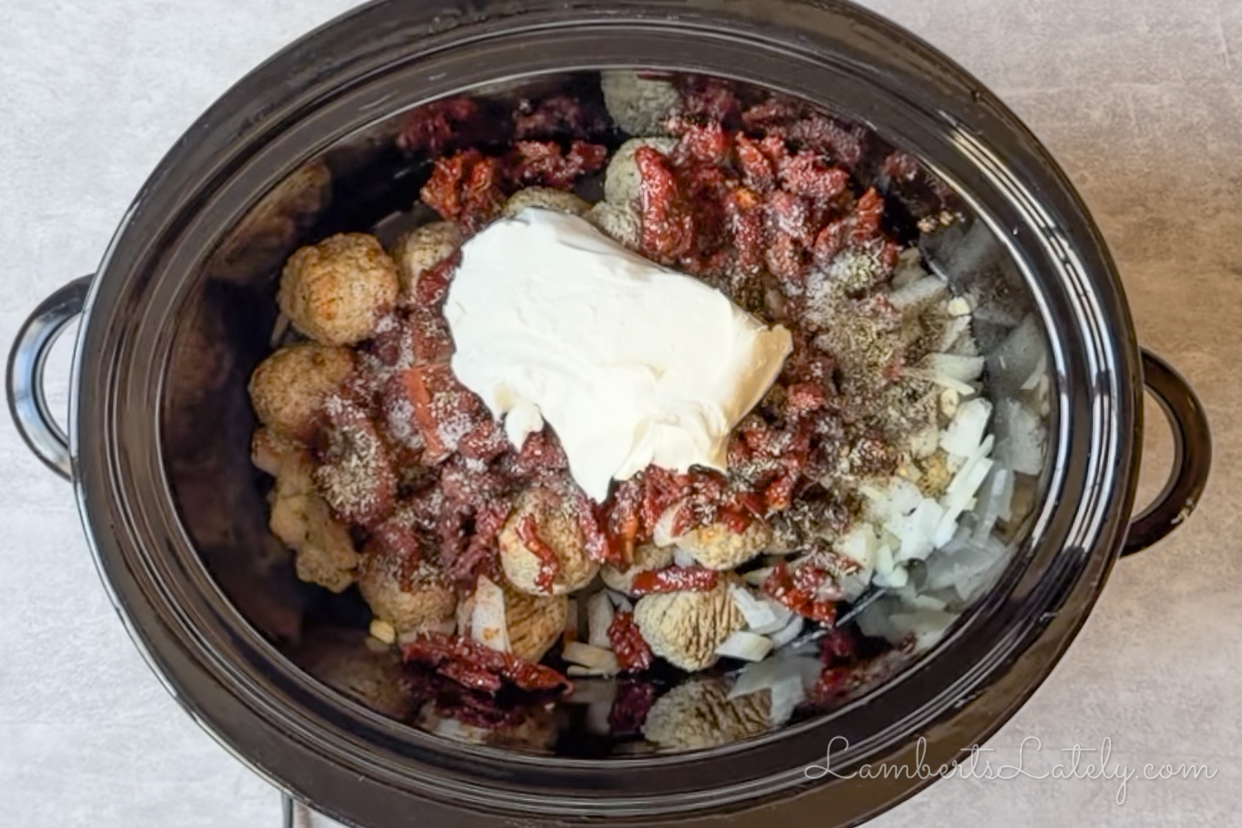 ingredients for marry me meatballs (frozen meatballs, cream cheese, sun dried tomatoes, spices, onion) in a crockpot.