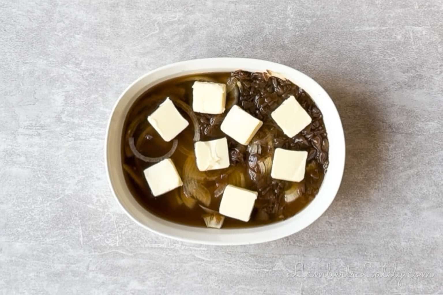 butter, french onion soup, onions, rice, and broth combined in a casserole dish.
