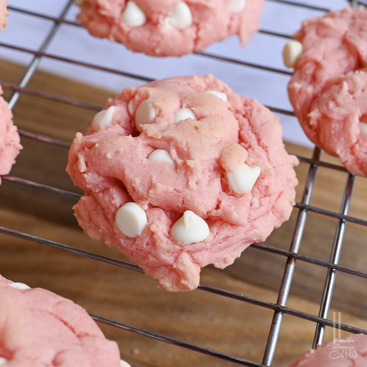 strawberry cake mix cookie with white chocolate chips on a baking rack.