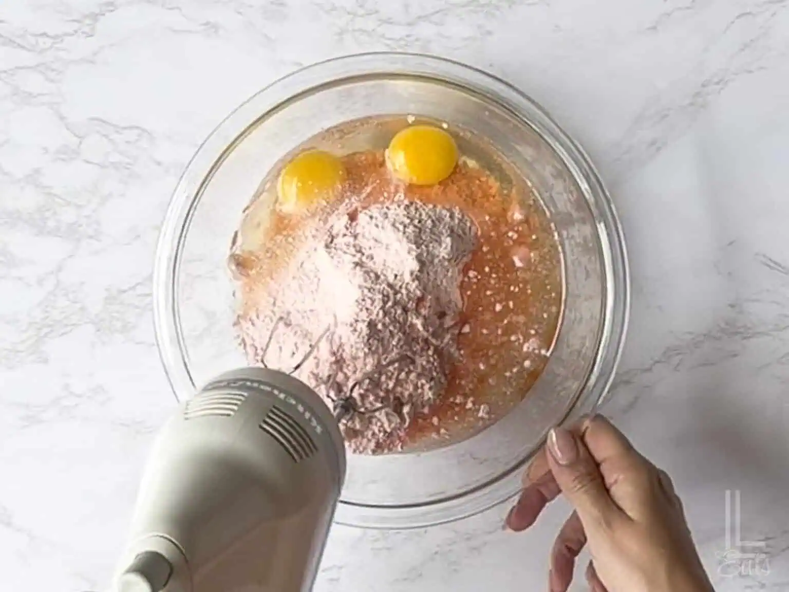 blending eggs, oil, and cake mix in a large glass bowl.
