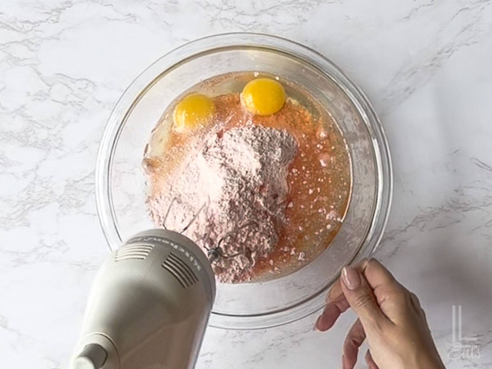 blending eggs, oil, and cake mix in a large glass bowl.