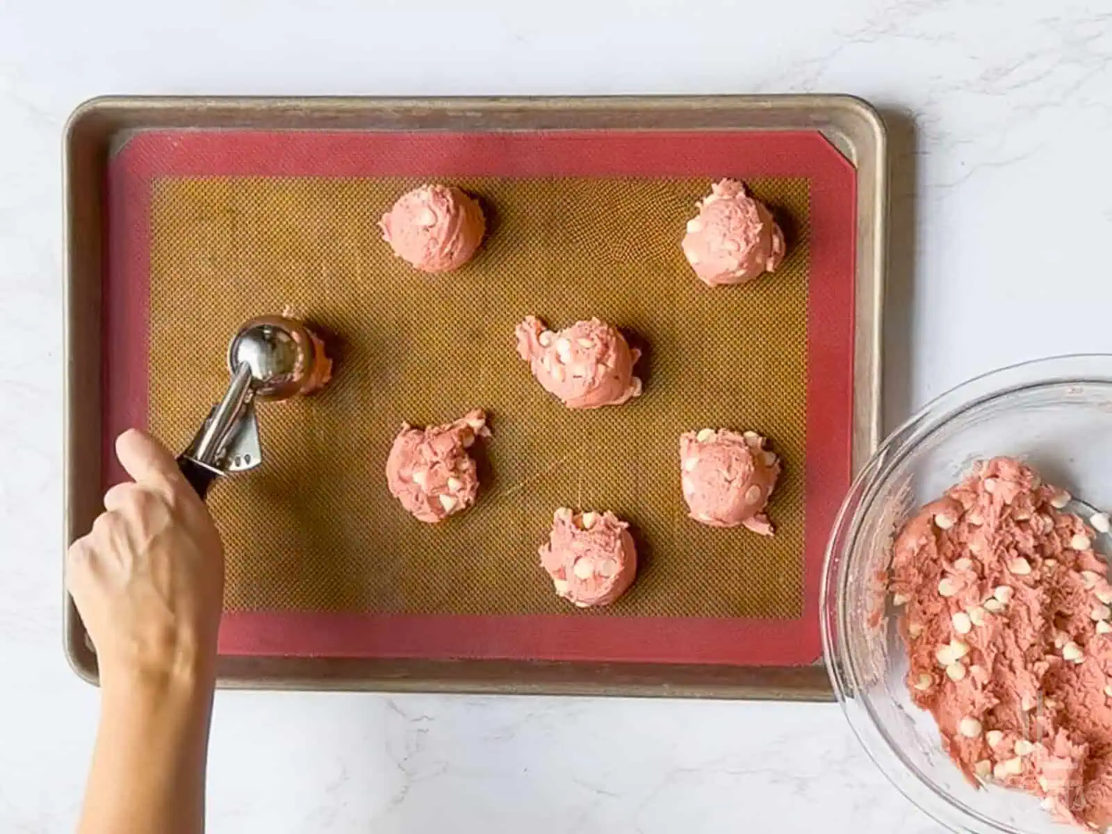 scooping cookie dough balls onto a baking sheet.