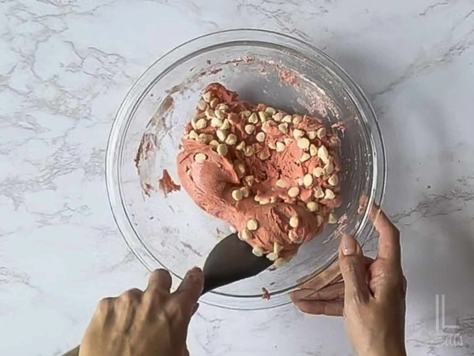 folding white chocolate chips into the cookie dough.