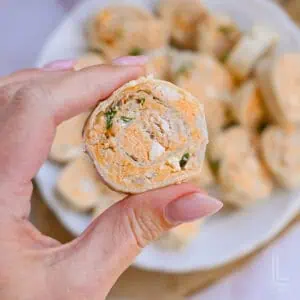 Buffalo chicken pinwheels with creamy filling and herbs on a white plate.