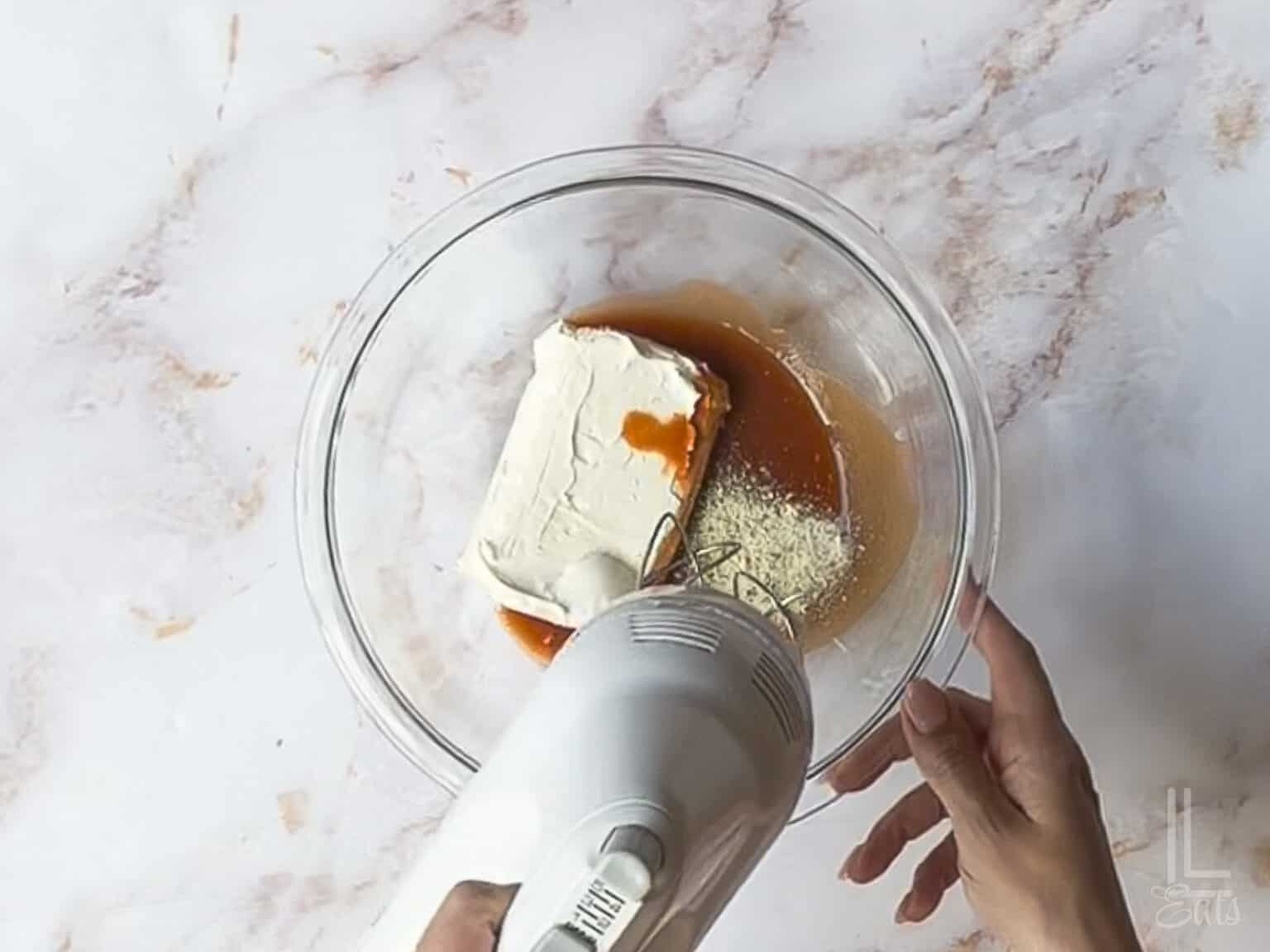 using a hand mixer to blend hot sauce, cream cheese, and ranch.