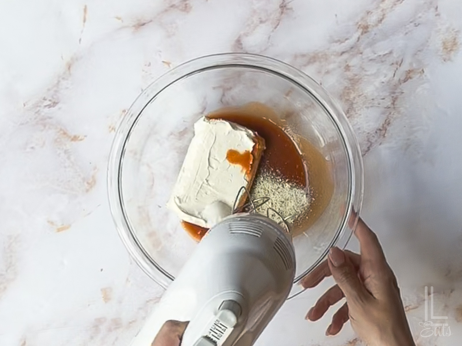 using a hand mixer to blend hot sauce, cream cheese, and ranch.