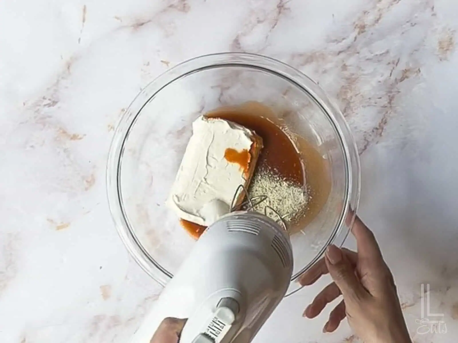 using a hand mixer to blend hot sauce, cream cheese, and ranch.