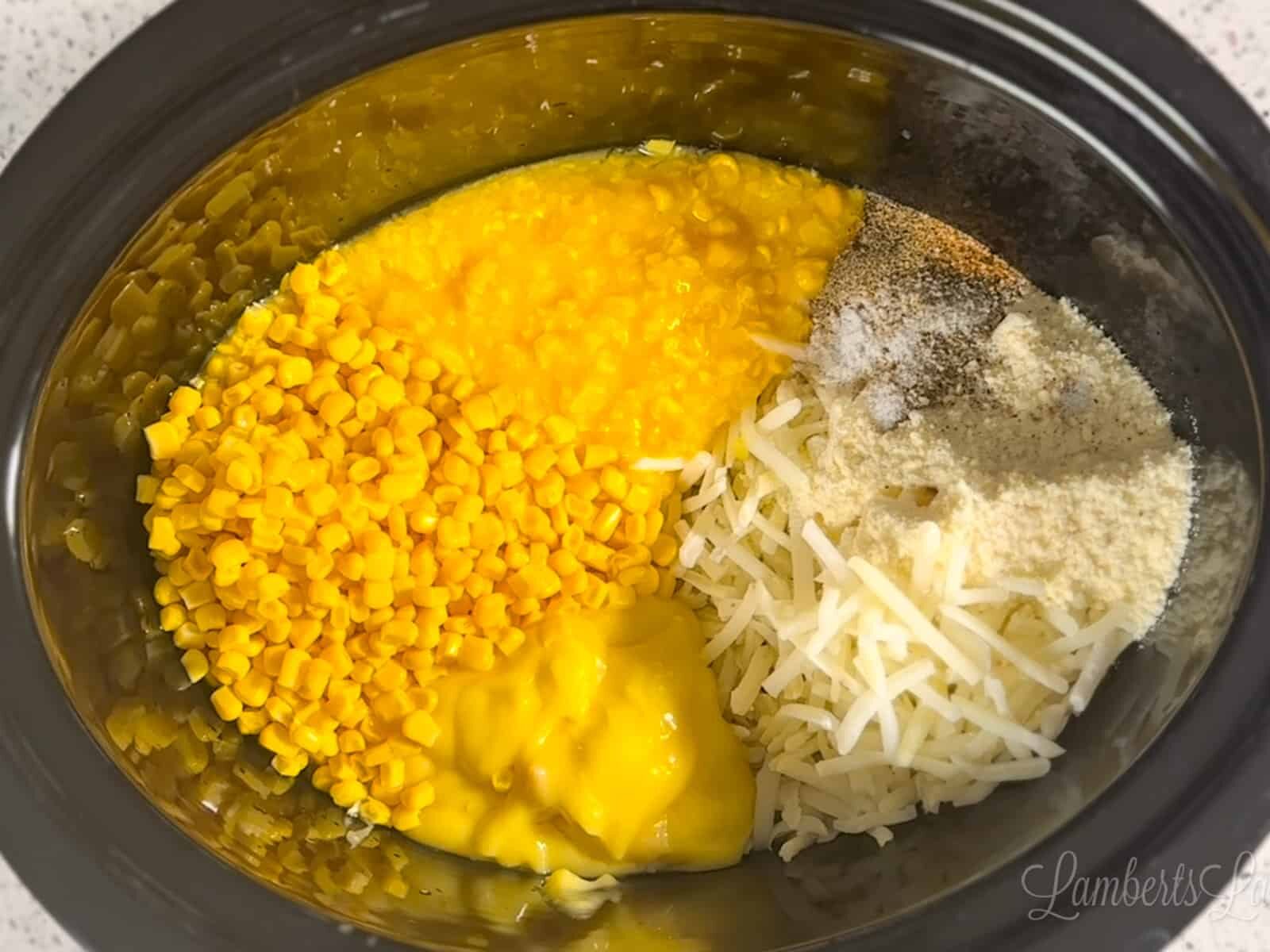 Mixing hash browns and corn in a Crock Pot for corn chowder base.