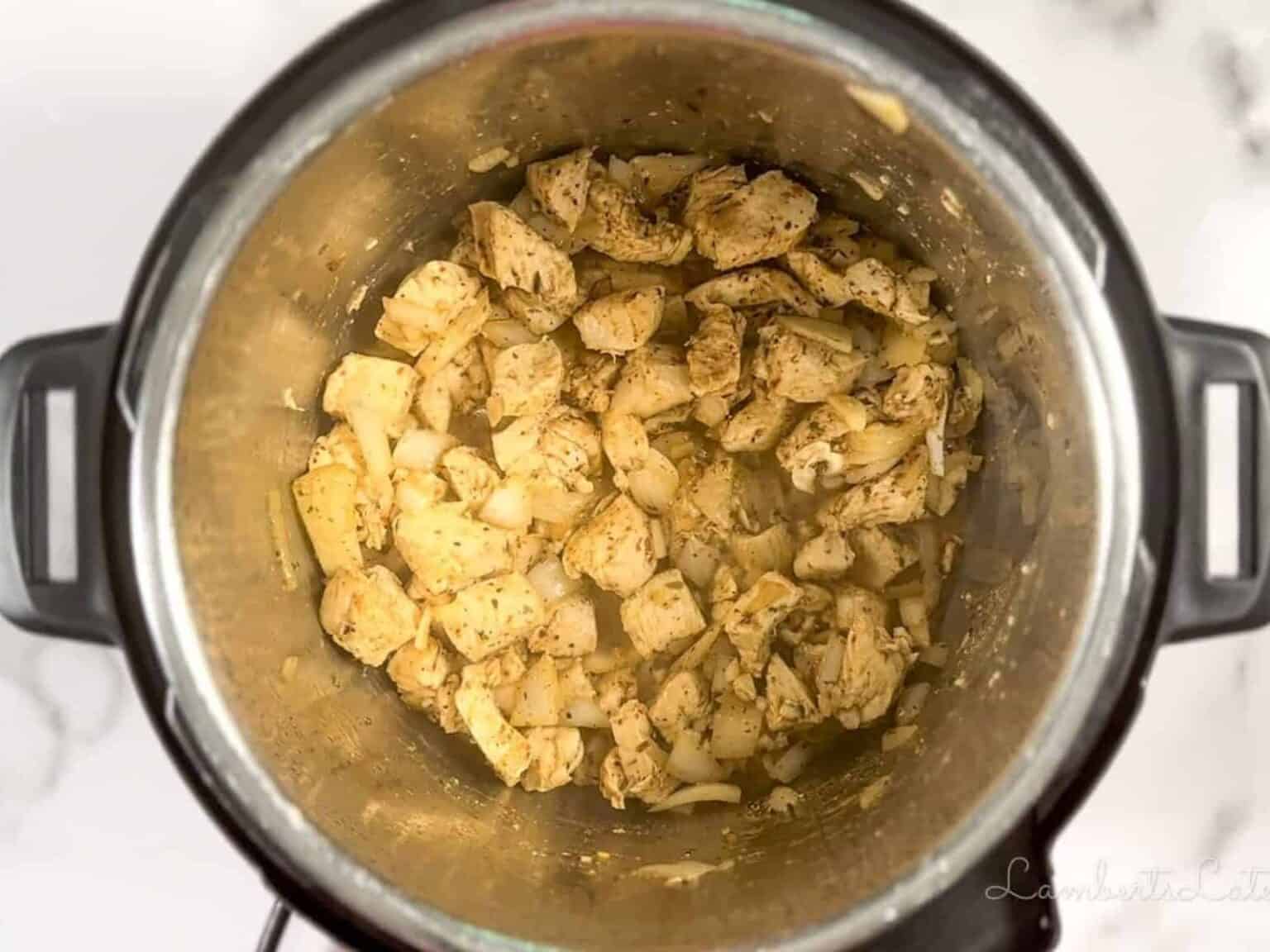 chicken, onion, and garlic cooking in an instant pot.