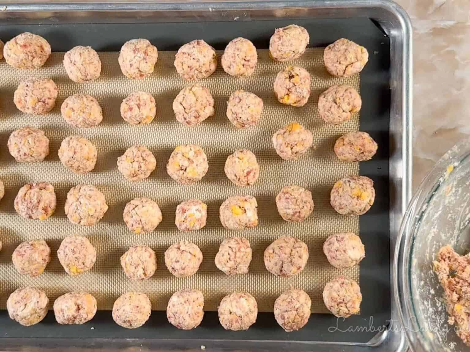 red lobster sausage balls rolled on a sheet pan.
