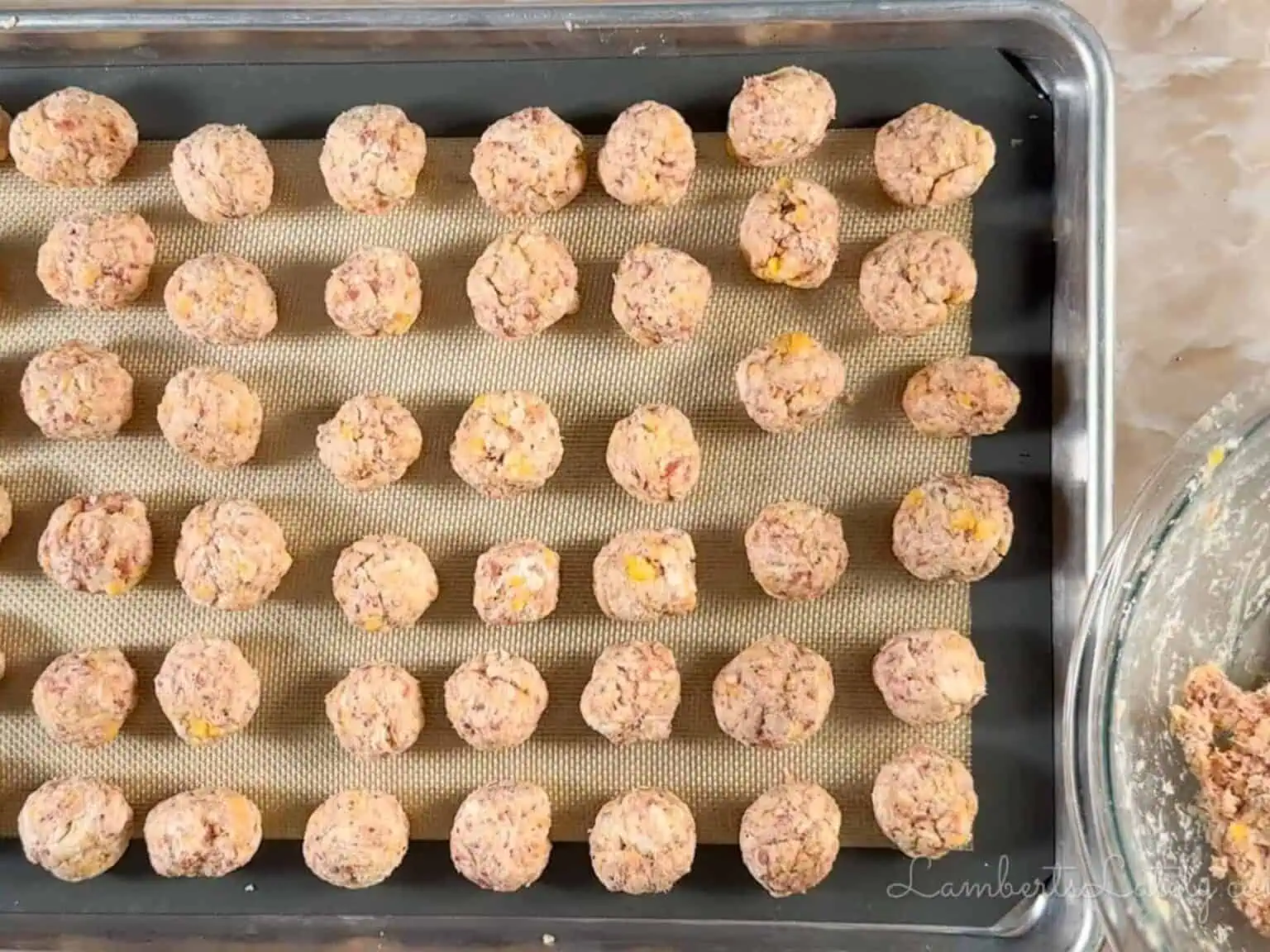 red lobster sausage balls rolled on a sheet pan.