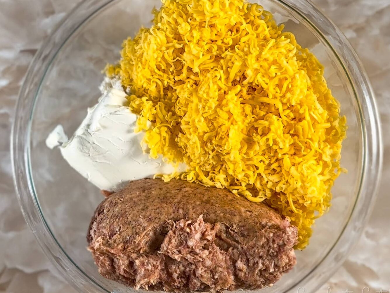 ingredients for cheddar bay sausage balls in a clear glass bowl.